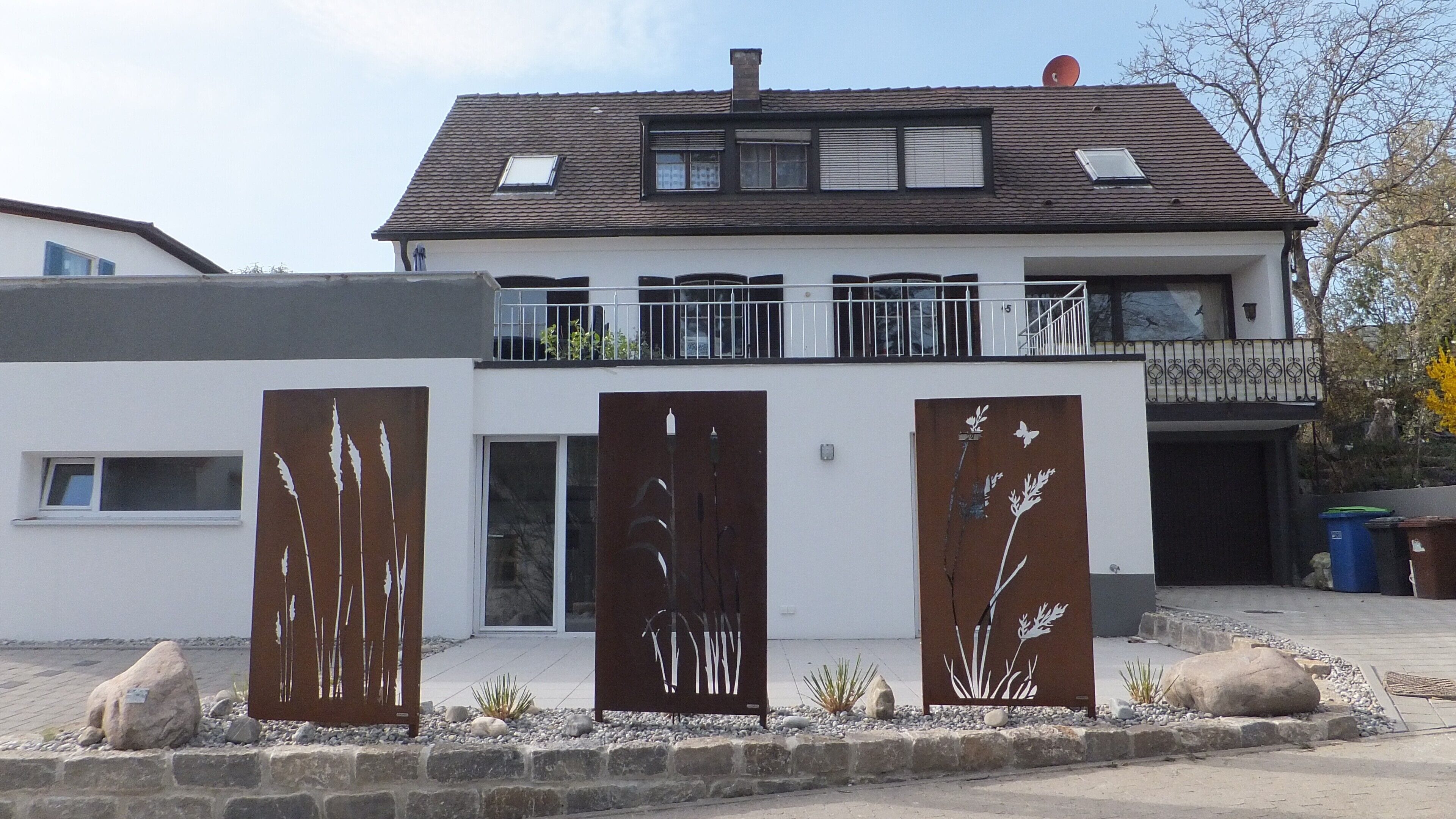 A two-story house with a balcony, a garage, and a decorative metal fence.
