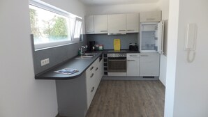 A compact kitchen with a built-in oven, a sink, and a window.