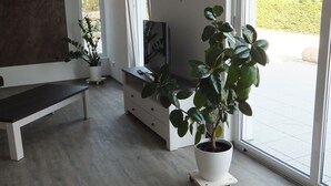 A modern interior with a bench, a TV stand, and potted plants.