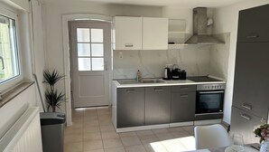 A modern kitchen with grey cabinets, a built-in oven, and a window. - Space for 4 (Unknown)
