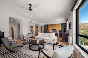 Una sala de estar moderna con un sofá blanco, una mesa de centro y un comedor con una cocina al fondo.