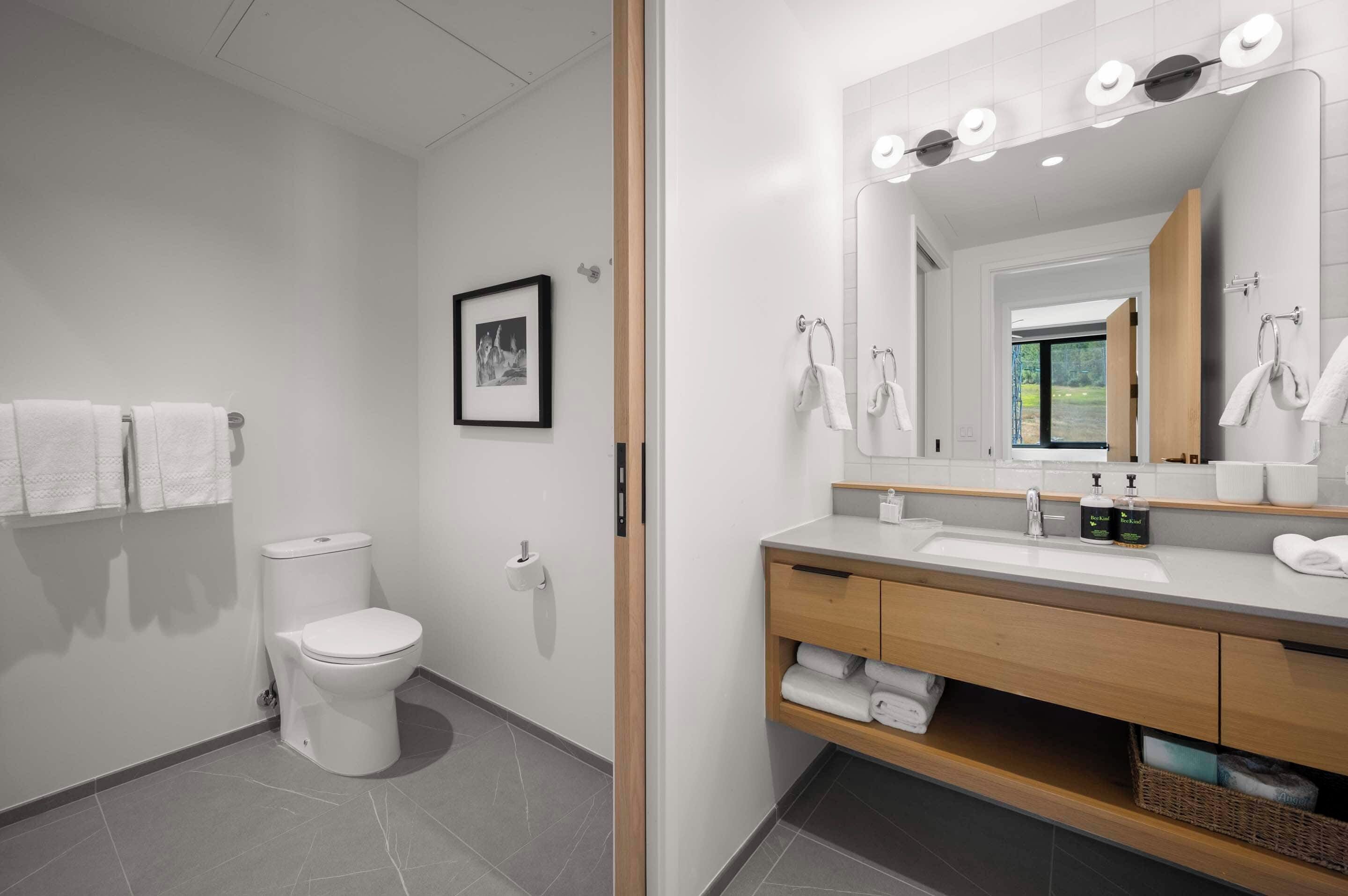 Un baño moderno con inodoro, lavamanos y espejo.