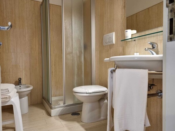 A modern bathroom with a glass shower enclosure, a toilet, a bidet, and a sink with a towel rack. - Hotel Virgilio (Orvieto)