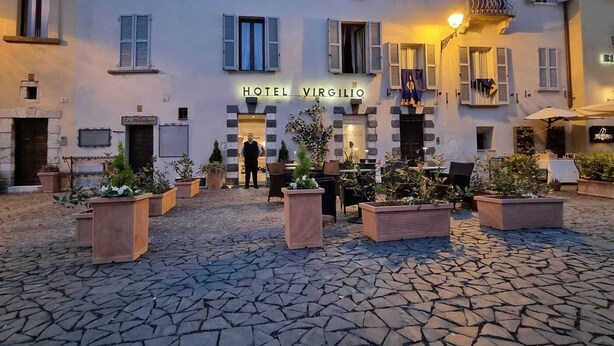 Un patio de hotel con pavimento de piedra, mobiliario exterior y una entrada acogedora.