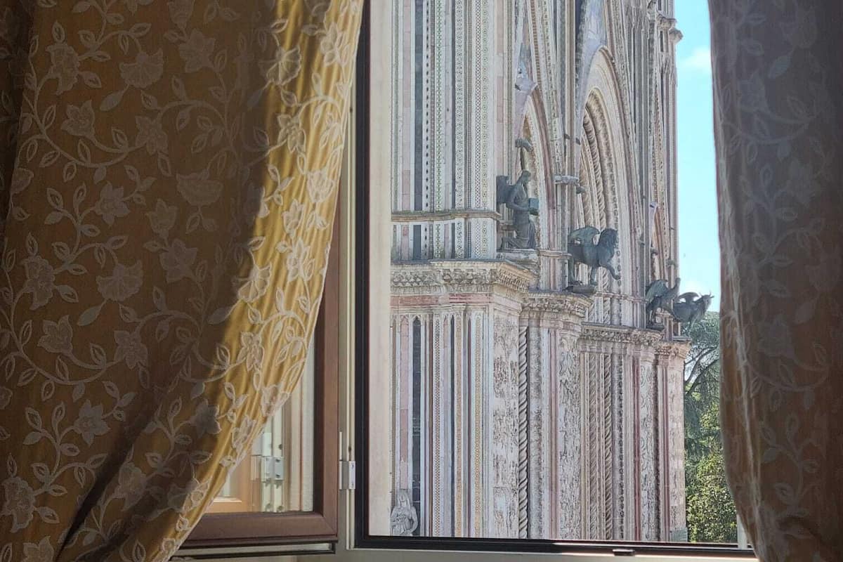 A room with a large window, curtains, and a view of a building with intricate architecture.
