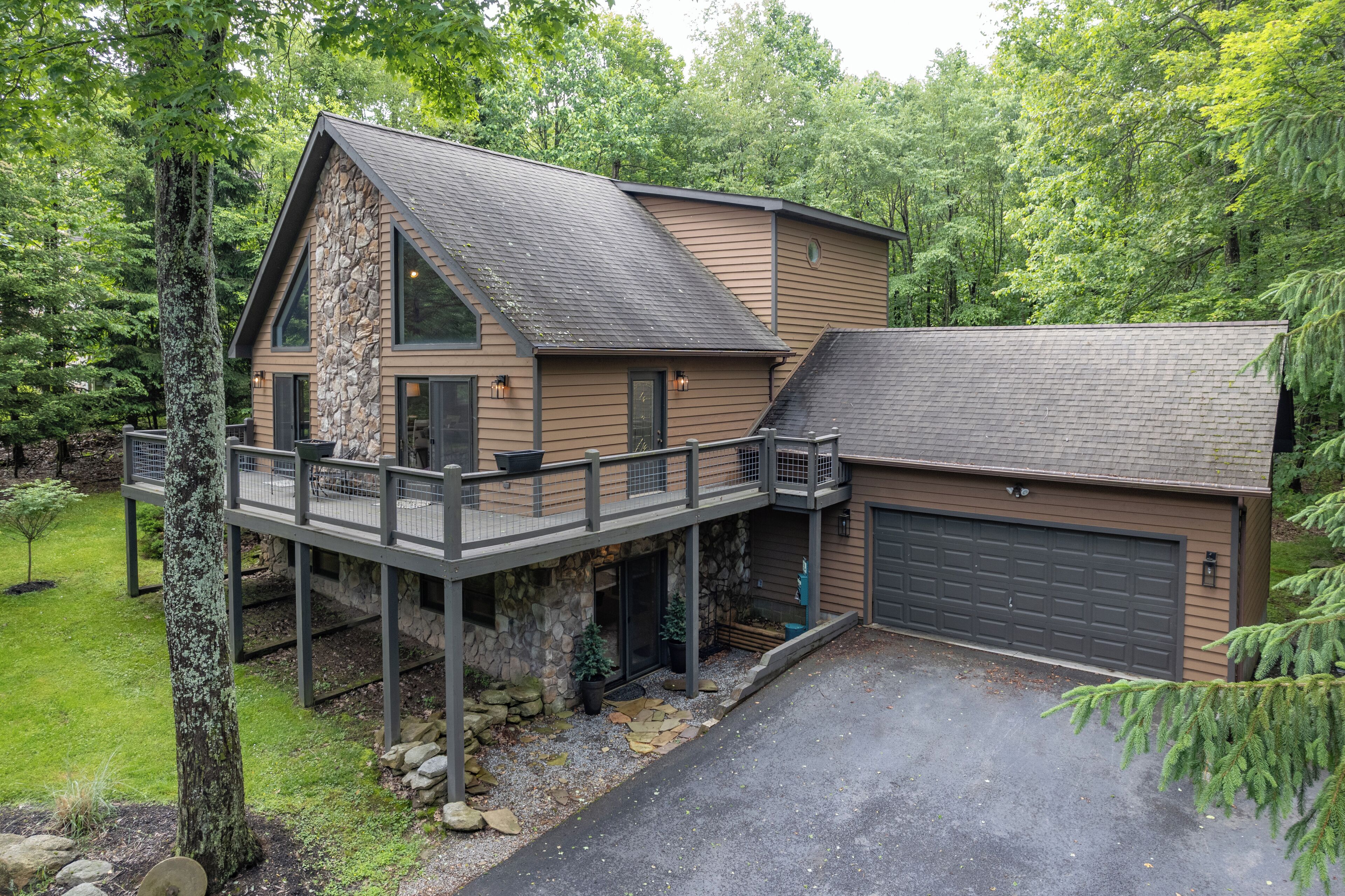 A two-story house with a stone facade, a balcony, and a garage.