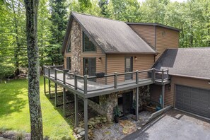 Une maison à deux étages avec des fondations en pierre, un balcon et un garage.