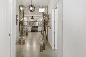Ein Flur, der zu einer Küche mit Treppe, einer Chandelier und Wanddekorationen führt.