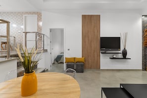 Ein modernes Wohnzimmer mit Fernseher, Sofa und Essbereich.