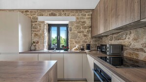 Een moderne keuken met stenen muren, witte kasten en een houten aanrecht.