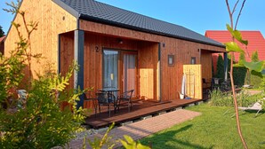 A wooden cabin with a deck, a door, and a window. - 2 Bedroom Holiday Home With air Conditioning (Postomino)