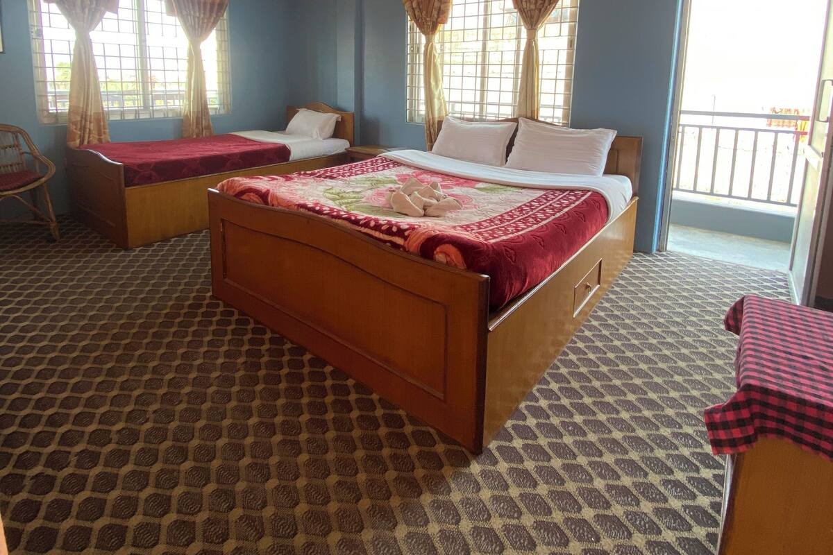 A room with two beds, a chair, and a balcony.