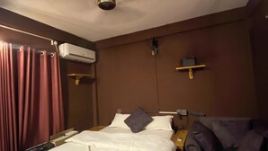 A hotel room with a bed, a chair, an air conditioning unit, and a ceiling fan. - Hotel Mountain Village (Pokhara)