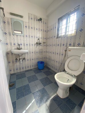 Un baño con un lavamanos blanco, un inodoro y una ducha. El piso está cubierto de azulejos con diseños azules y blancos.