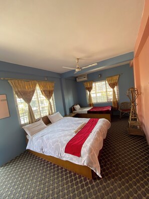 Habitación de hotel con dos camas, ventilador de techo y alfombra estampada.