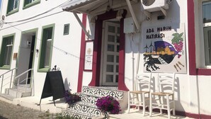 Un edificio con un letrero que dice "ADA MARIN HATIRASI" y vista al mar con molinos de viento.