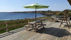 Un pontile in legno con tavoli da picnic e un ombrellone che si affaccia su uno specchio d'acqua.