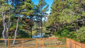 Un espace extérieur clos, doté d’un bassin, entouré d’arbres et agrémenté d’une terrasse en bois.