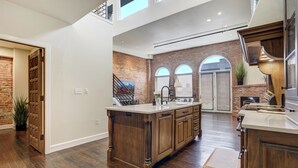 Un'ampia cucina con una grande isola, mobili in legno e una parete decorata in mattoni.