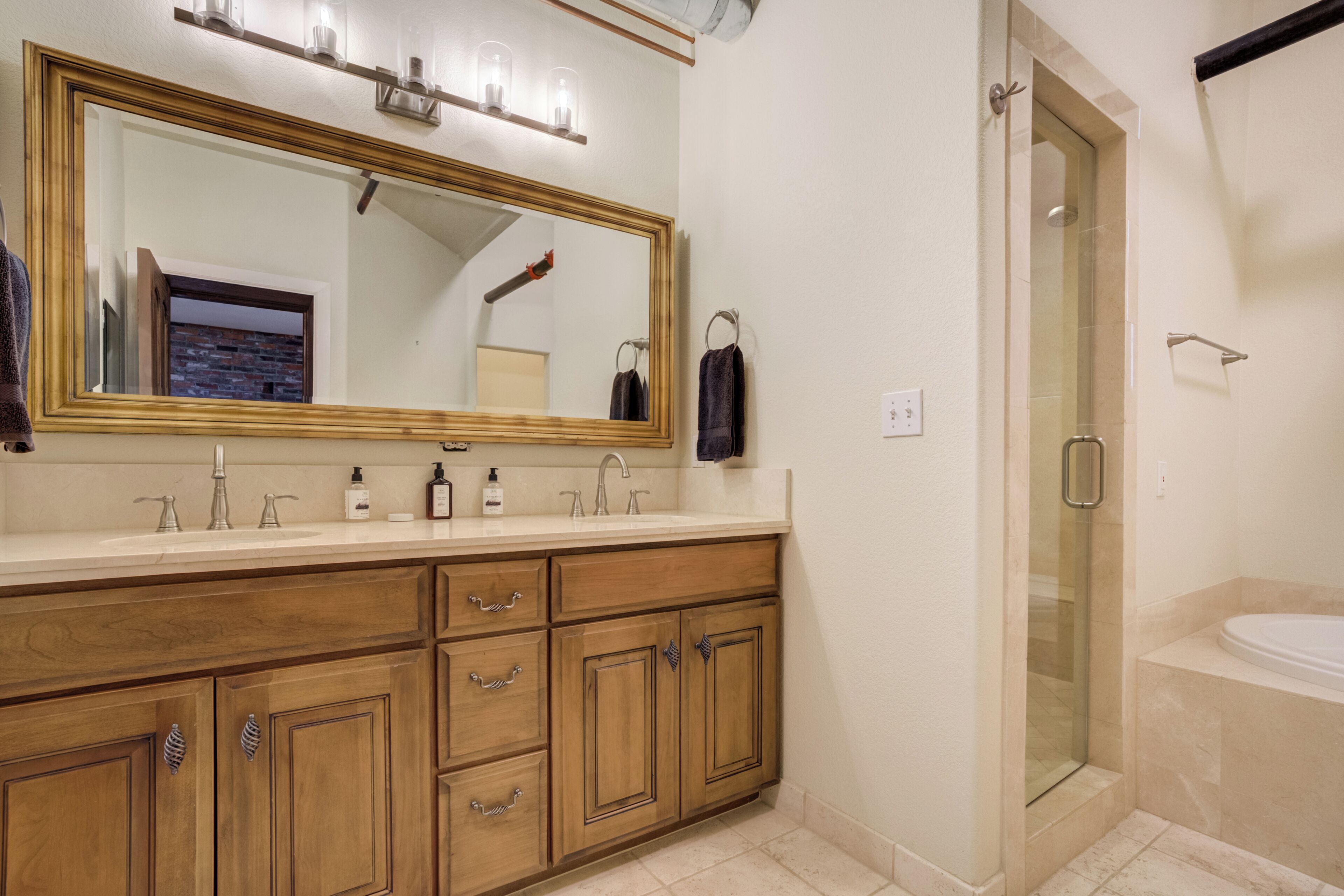 A bathroom with a large mirror, wooden vanity, a shower enclosure, and a bathtub.