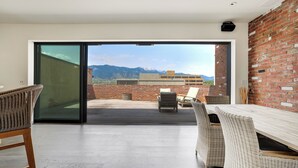 Un ampio balcone con vista sulle montagne, mobili in vimini e un muro in mattoni.