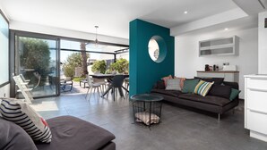 A modern living room with a sofa, a coffee table, and a dining area with chairs and a table. - Villa in Le Grau du Roi with Stunning Sea Views (Le Grau-du-Roi)
