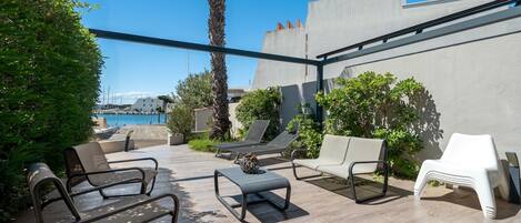 Terraza en la azotea con mobiliario exterior, una palmera y vistas al mar.