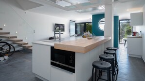 A modern kitchen with a central island, built-in oven, and bar stools. - Villa in Le Grau du Roi with Stunning Sea Views (Le Grau-du-Roi)