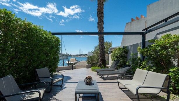 An outdoor patio with lounge chairs, a table, and a view of the sea. - Villa in Le Grau du Roi with Stunning Sea Views (Le Grau-du-Roi)