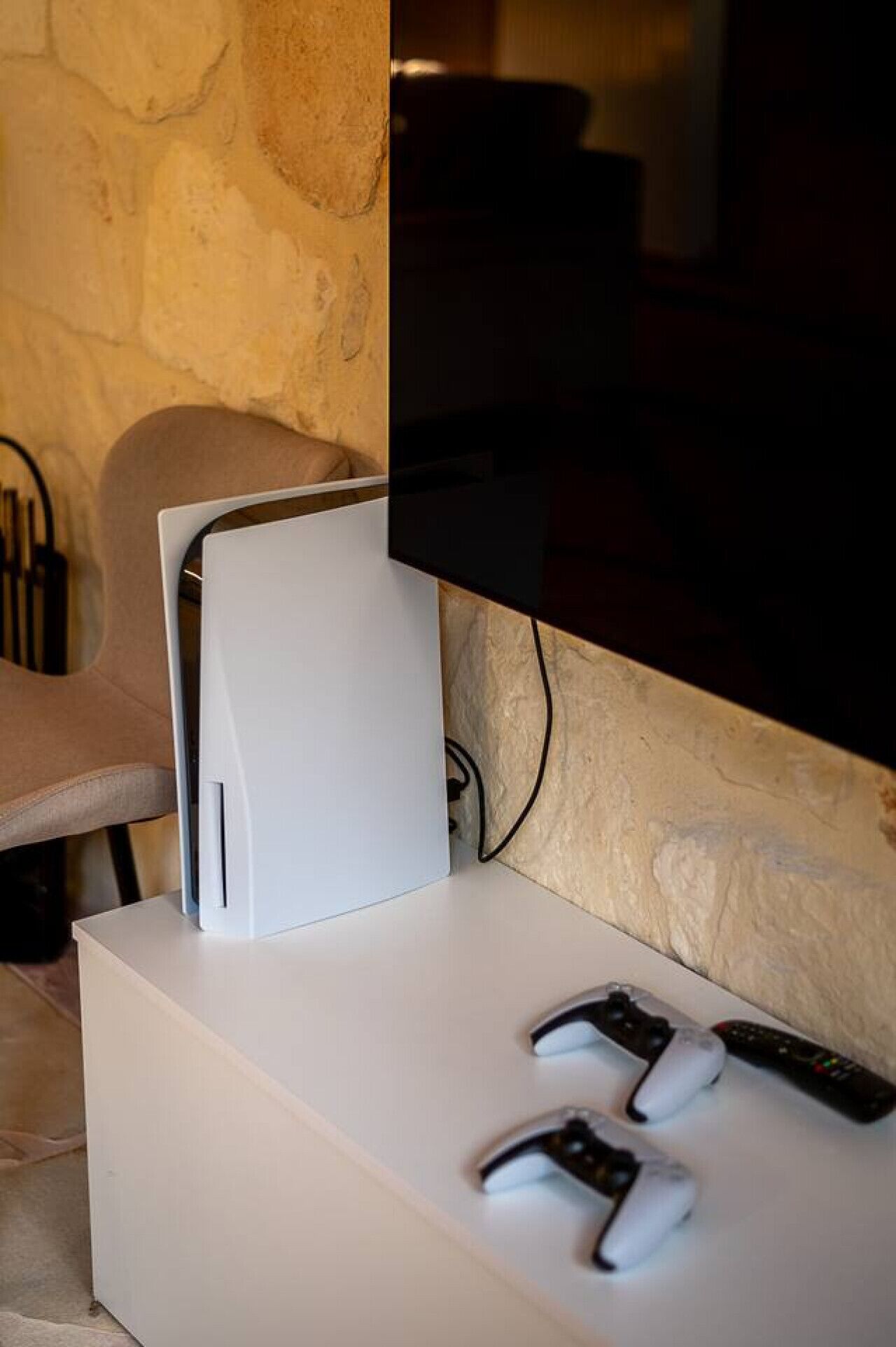 Een witte gameconsole op een wit oppervlak, met twee controllers en een afstandsbediening.