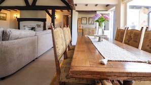 Un espace repas avec une longue table en bois, des chaises rembourrées et un arrangement floral en guise de décoration centrale.
