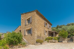Un bâtiment en pierre avec un toit à deux versants, un petit porche et une fenêtre avec des volets.