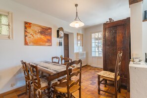 A dining area with a wooden table, chairs, and a large painting on the wall.