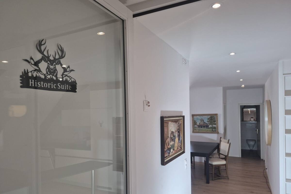 A room with a dining table, chairs, and a painting on the wall.