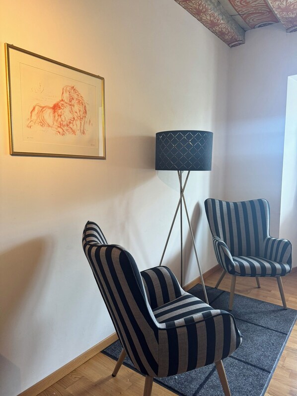 Una habitación con dos sillones a rayas, una lámpara de pie y un cuadro enmarcado en la pared.