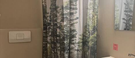 Een badkamer met toilet, wastafel en douchegordijn met een natuurprint.