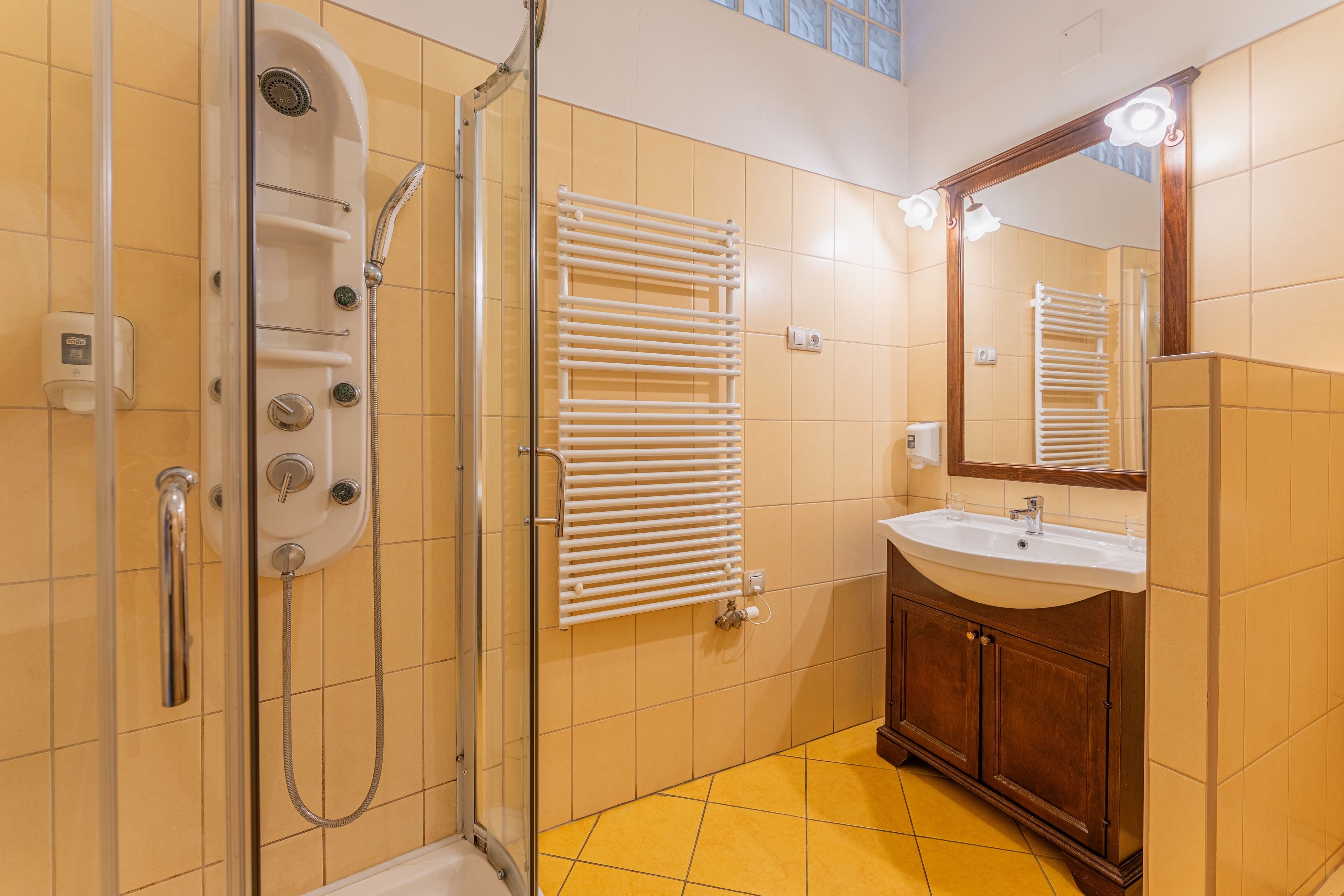 A bathroom with a glass-enclosed shower, a white sink, and a wooden vanity.