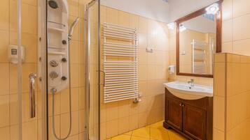 A bathroom with a glass-enclosed shower, a white sink, and a wooden vanity.