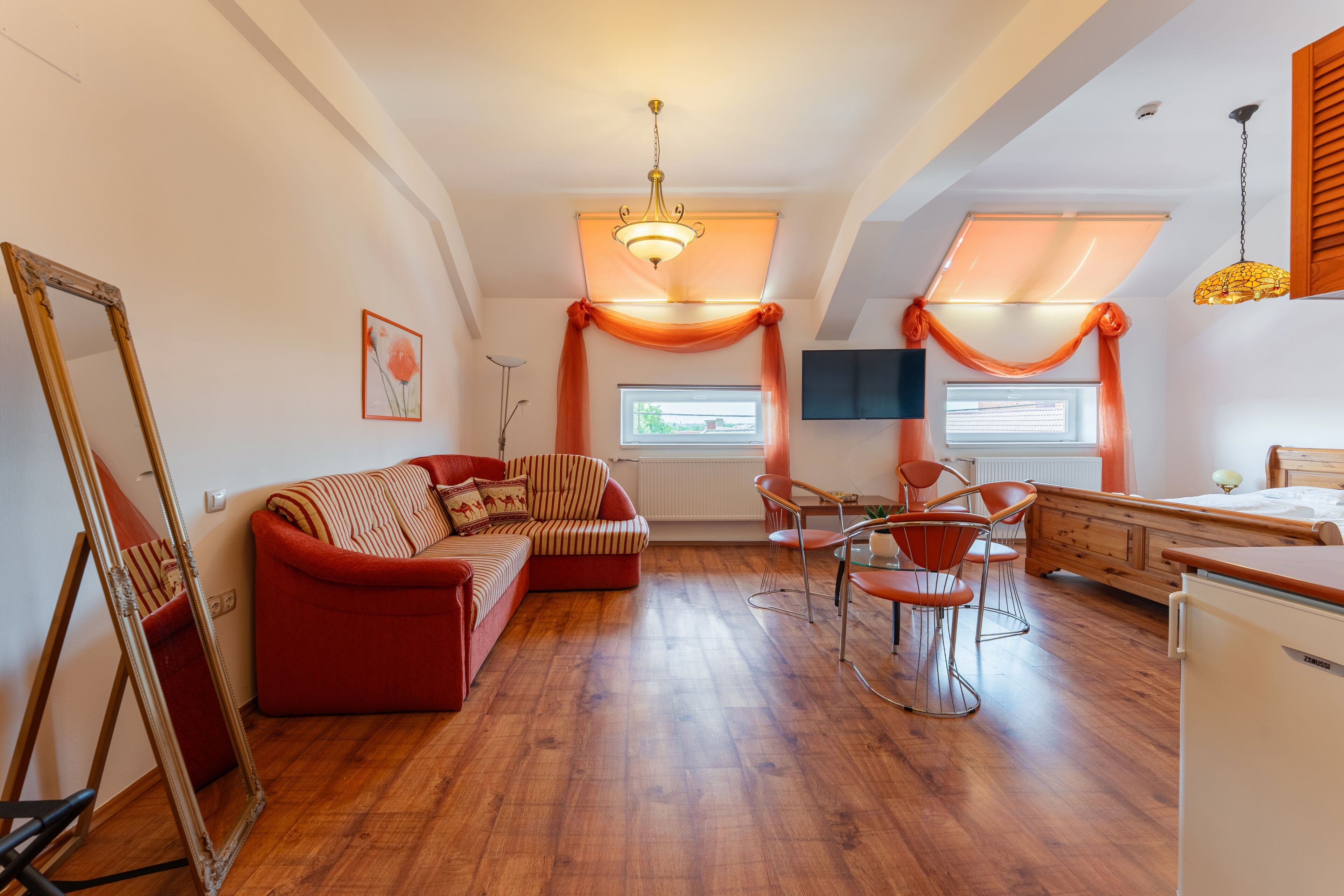 Una sala acogedora con un sofá, sillas, una mesa de comedor y un televisor.