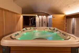 Un jacuzzi con múltiples chorros, rodeado de paneles de madera y un muro de azulejos.