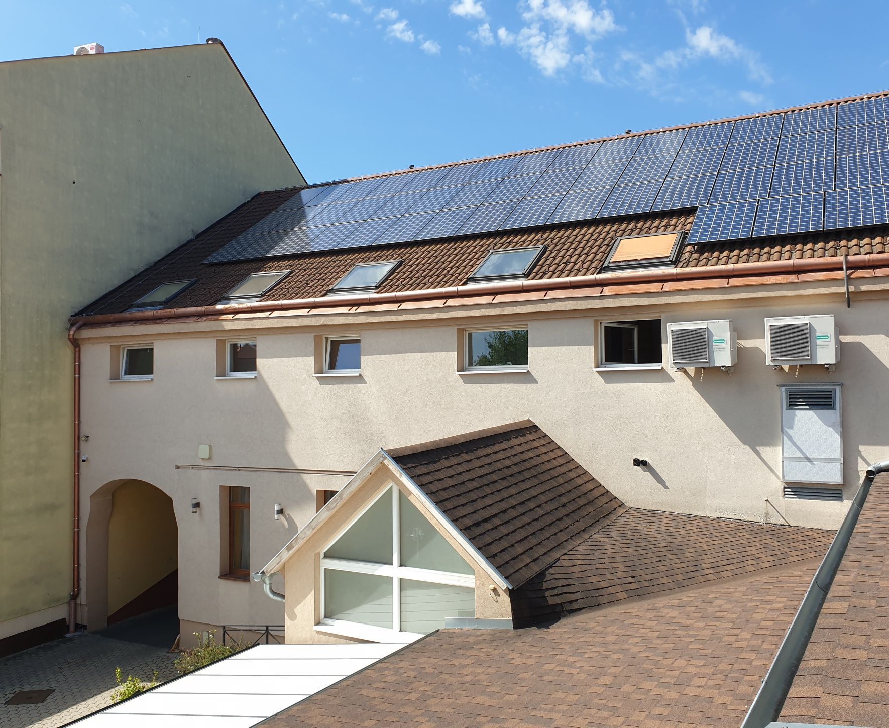 Un bâtiment doté d’un toit en pente, de nombreuses fenêtres et d’un garage attenant.