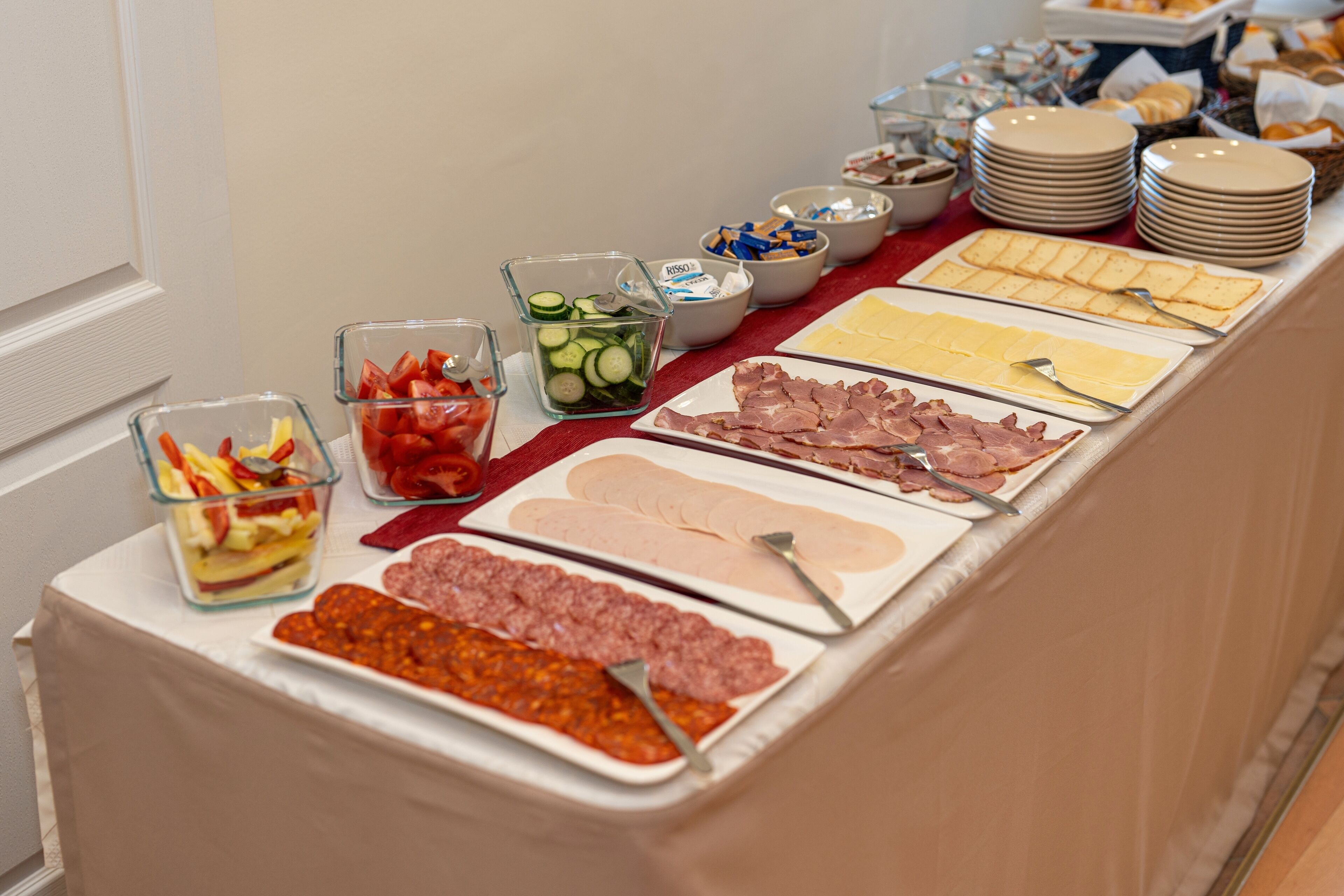 A buffet table with various food items including sliced meats, cheeses, and vegetables.