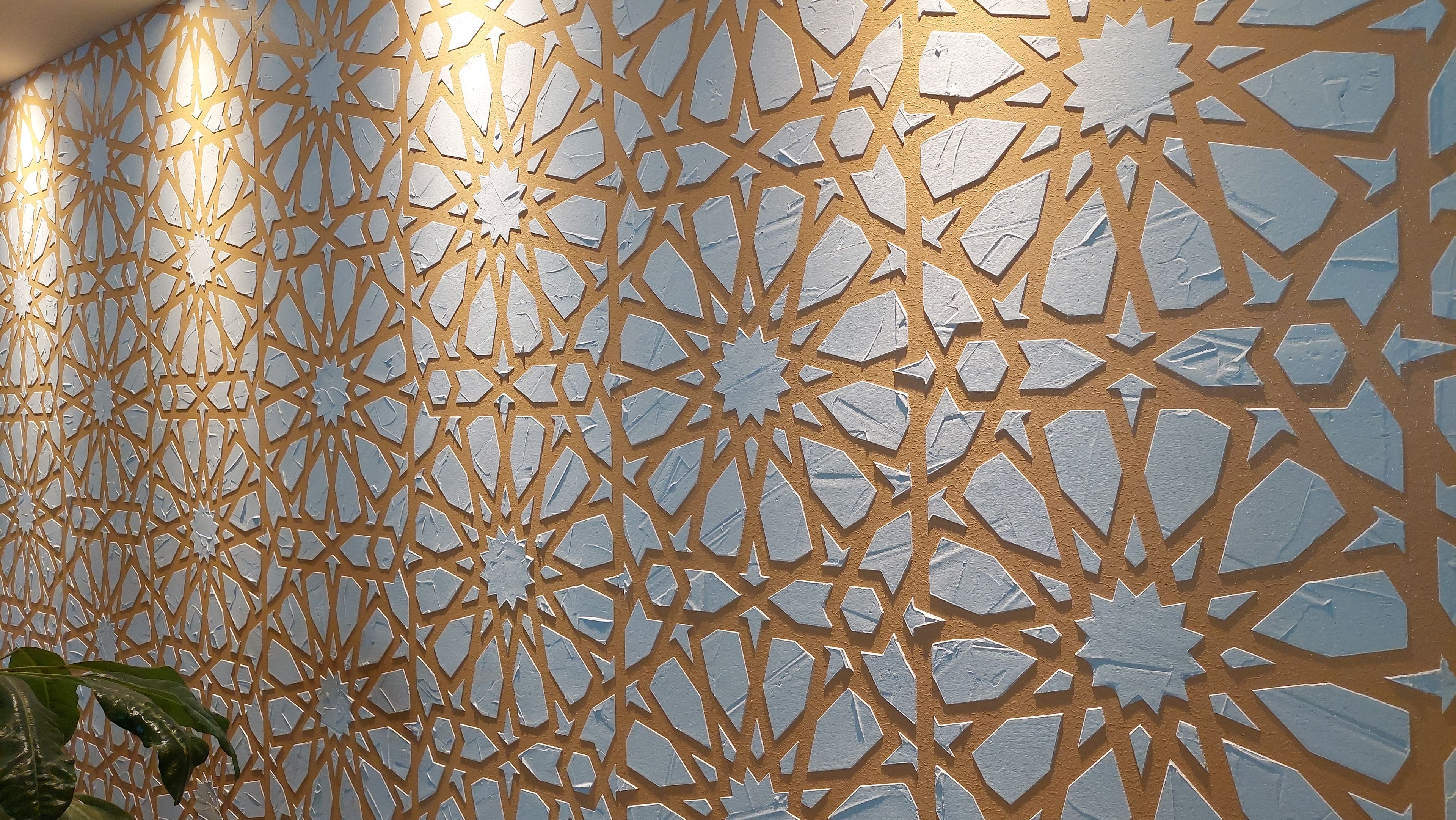 Paredes com padrão geométrico em branco e dourado.
