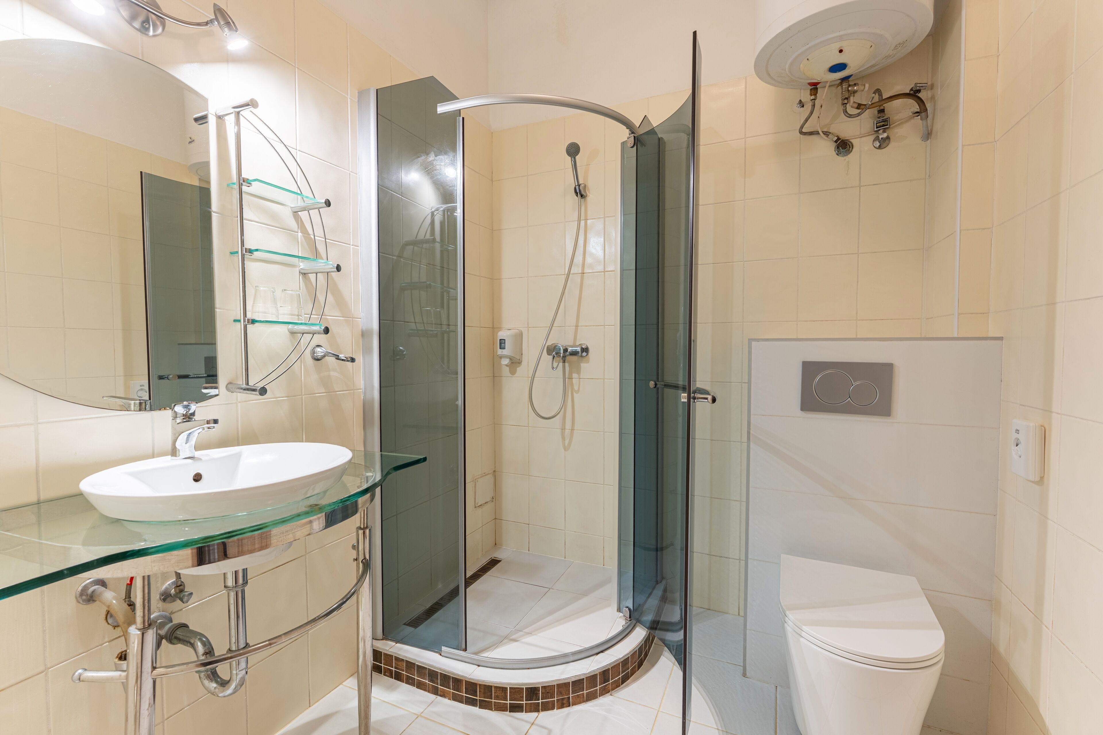 Uma casa de banho moderna com chuveiro separado por vidro, lavatório de vidro e sanita.