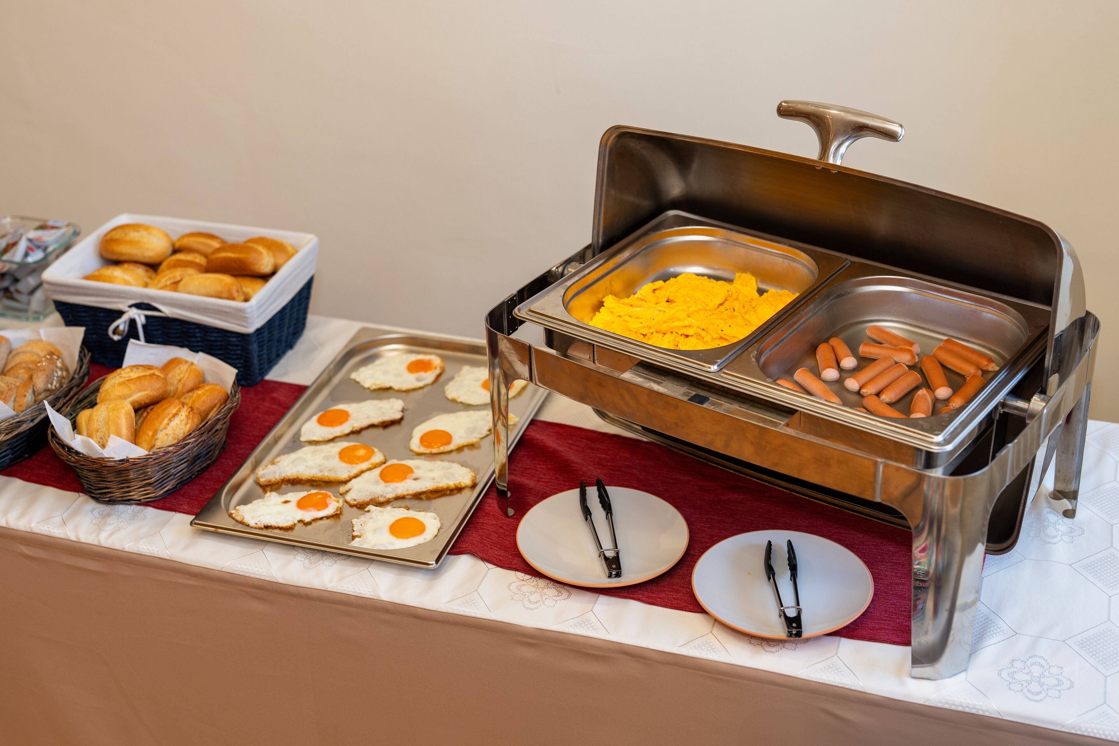 A buffet with various food items including eggs, sausages, and pastries.