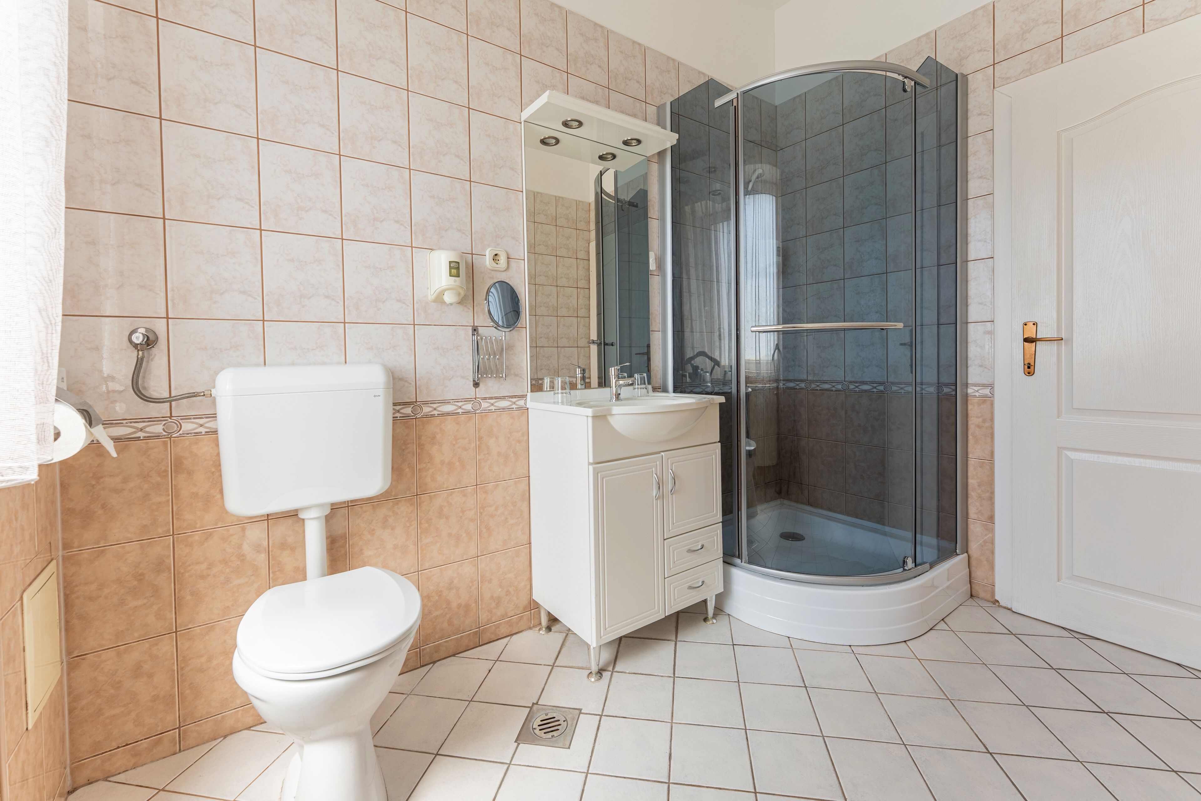 Une salle de bain avec des toilettes, un lavabo et une douche.