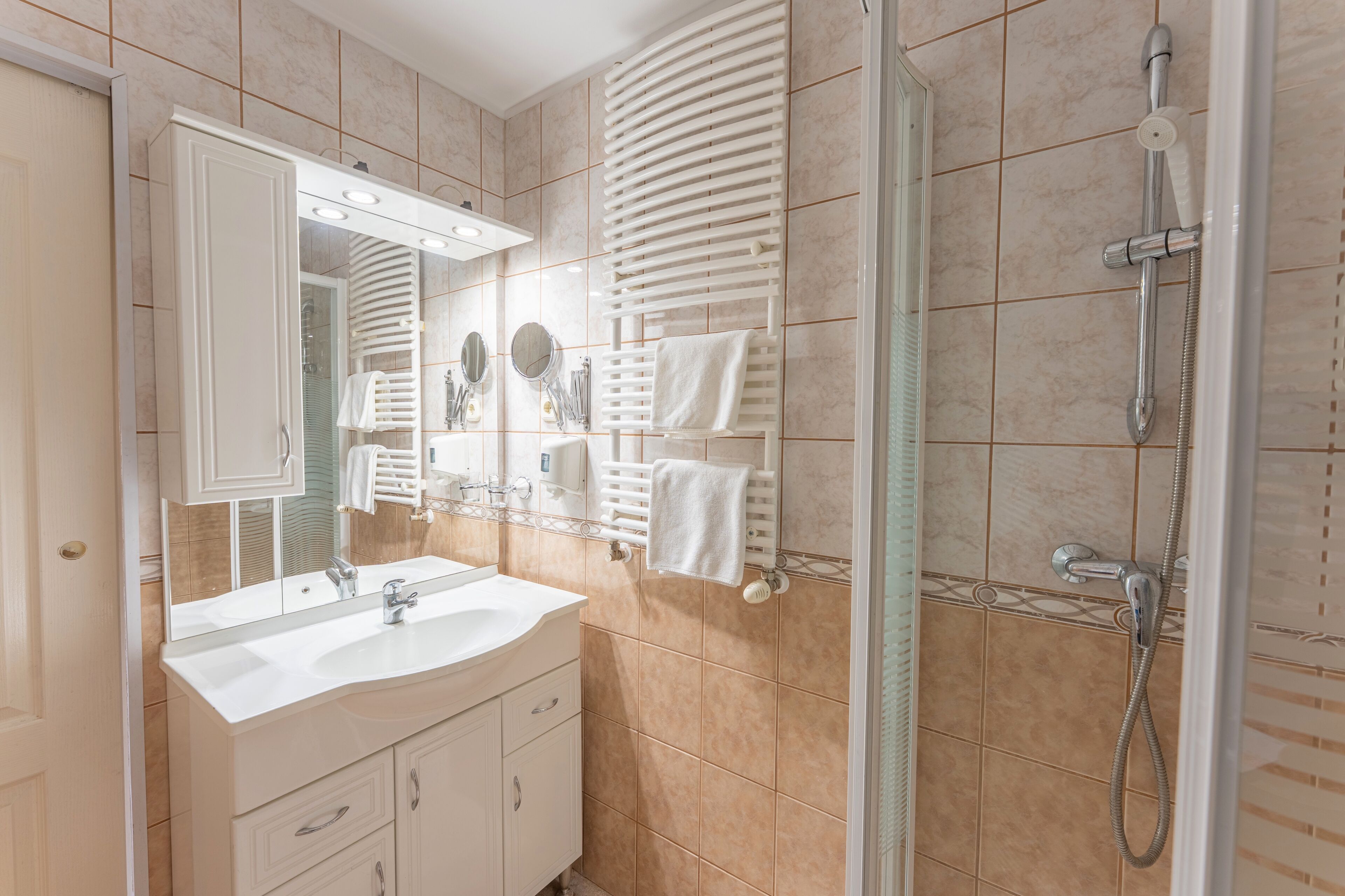 Un baño moderno con un espejo grande, dos lavamanos, una ducha y un perchero para toallas.