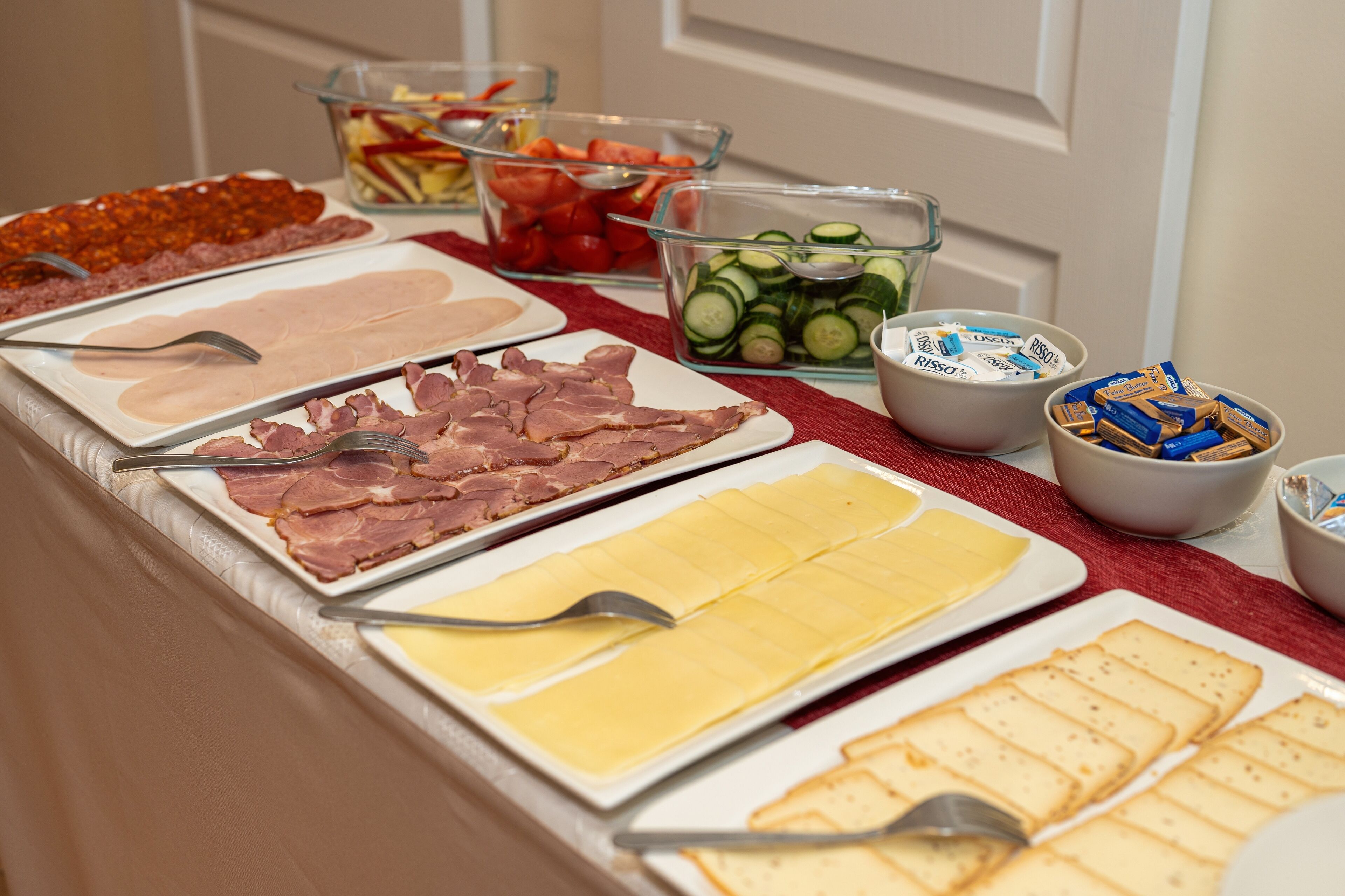 Ein Buffet mit verschiedenen Speisen, darunter Fleisch, Käse und Gemüse.
