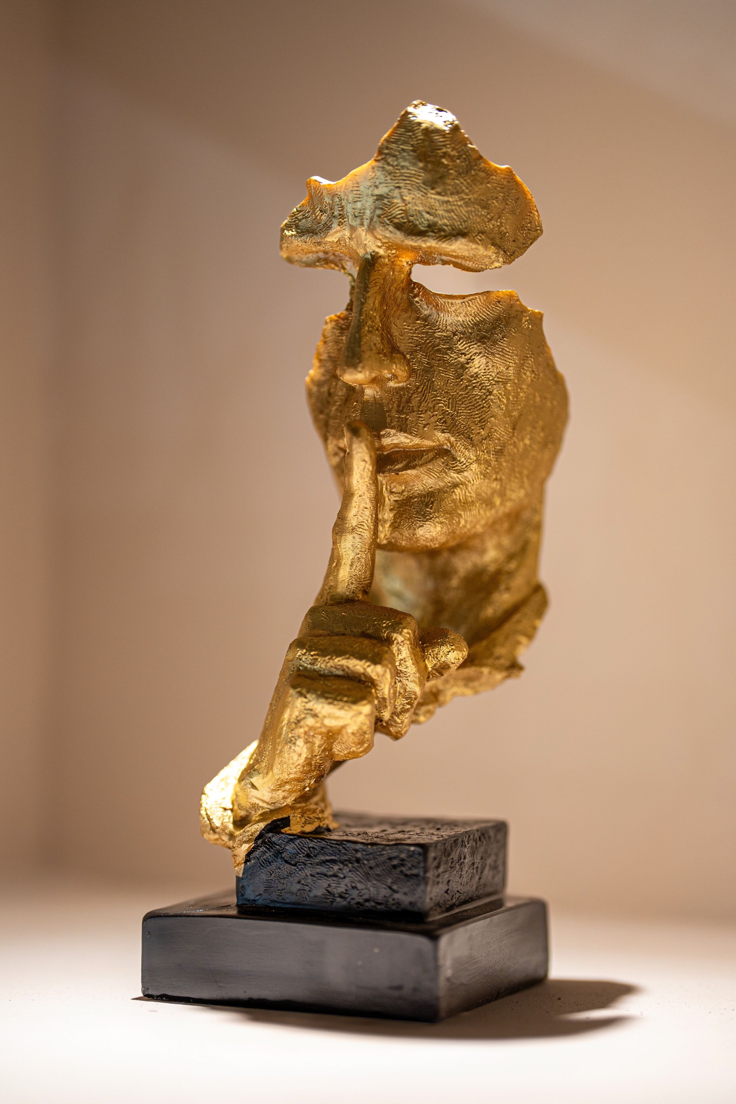 A sculpture of a human figure in a dynamic pose, mounted on a dark rectangular base.