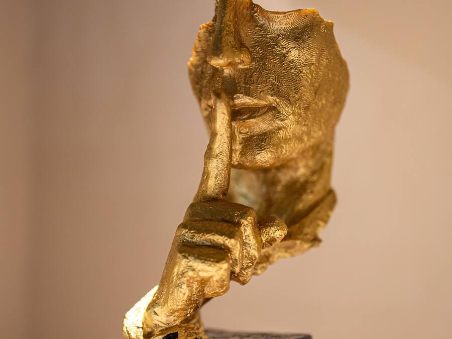 Una escultura de figura humana en una pose dinámica, sobre un pedestal rectangular oscuro.